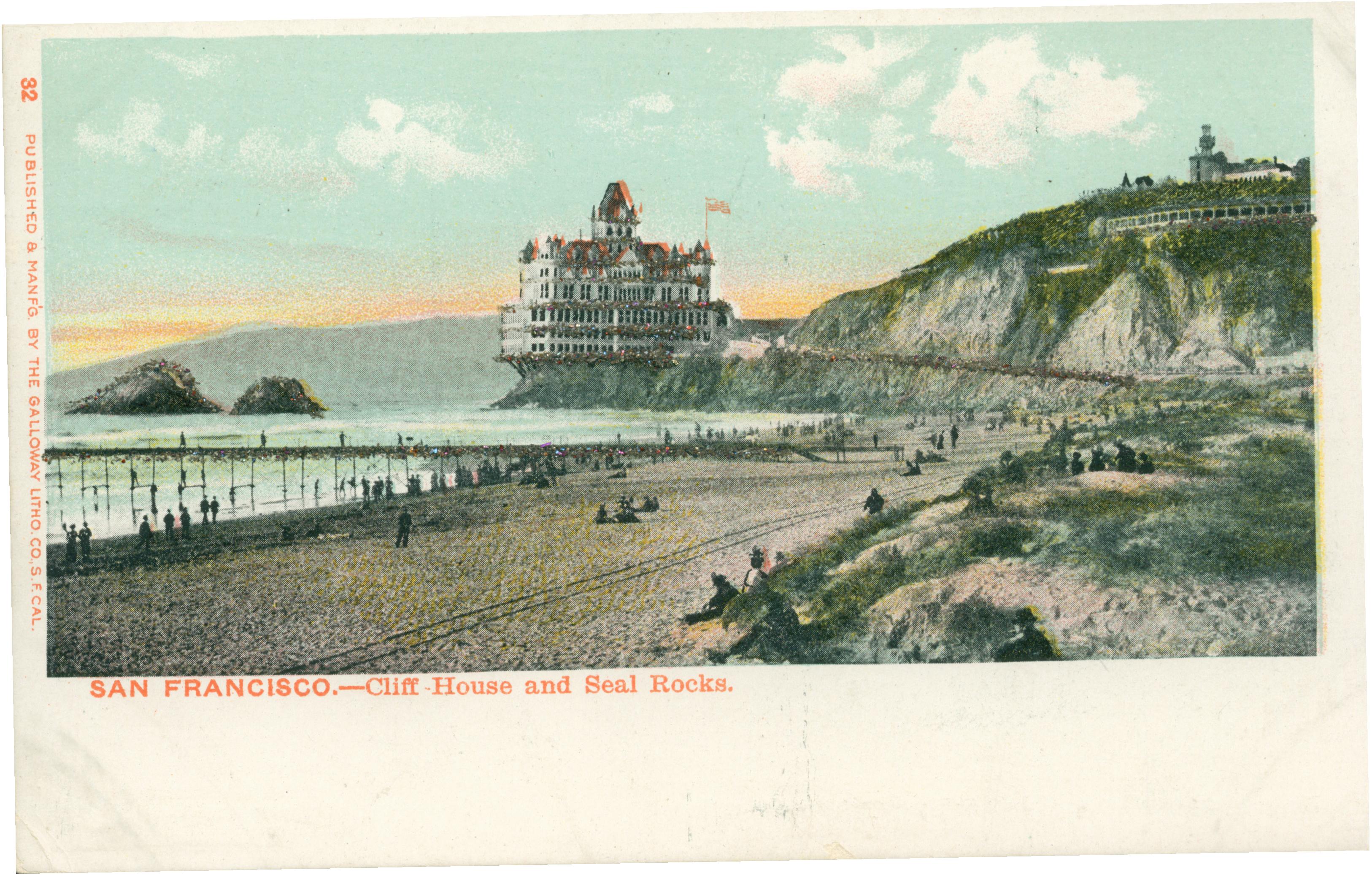 Shows the Cliff House and Seal Rocks, with a jetty and several individuals on the beach in the foreground.